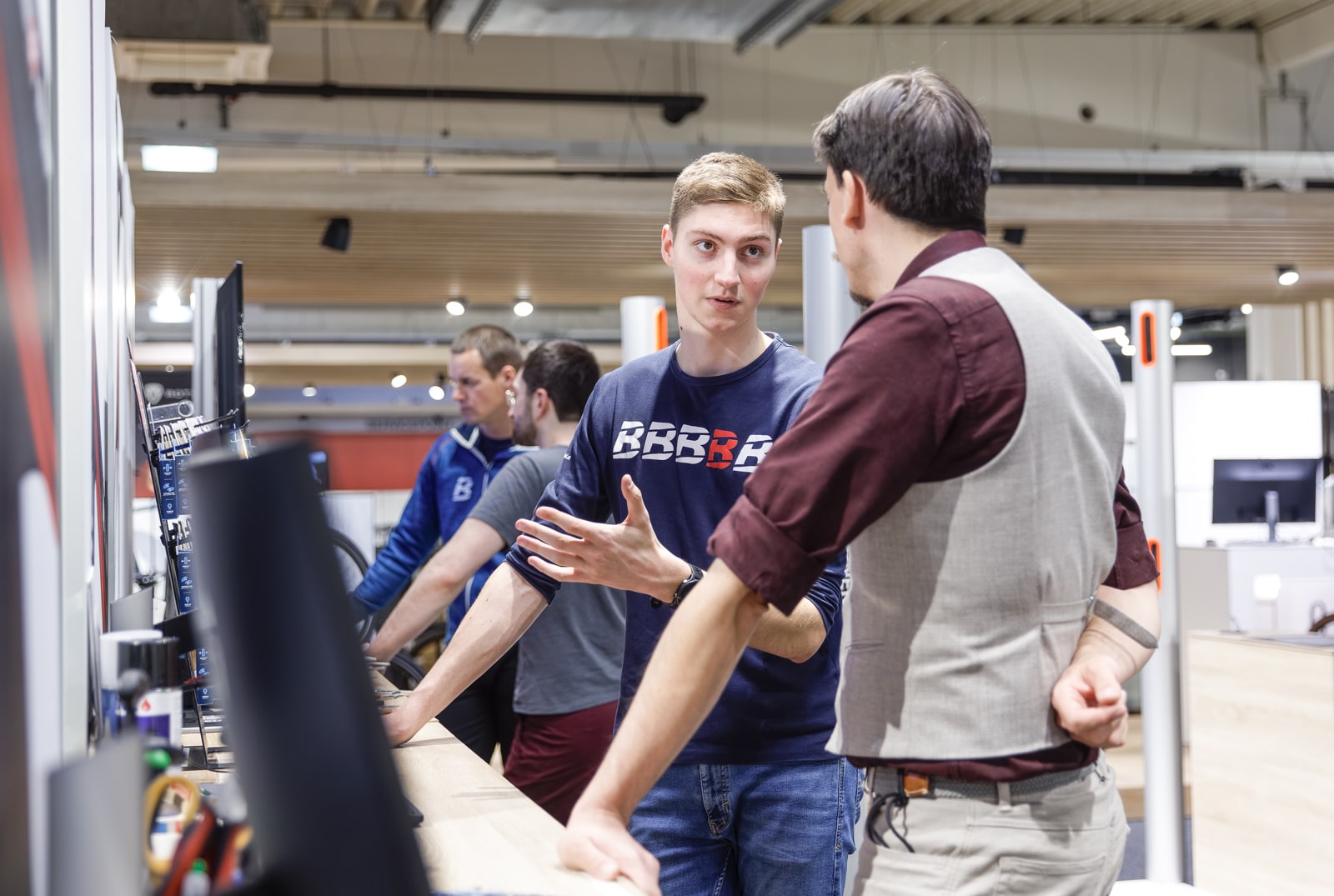 a young man in a bernhard kohl branded t-shirt is talking to a customer